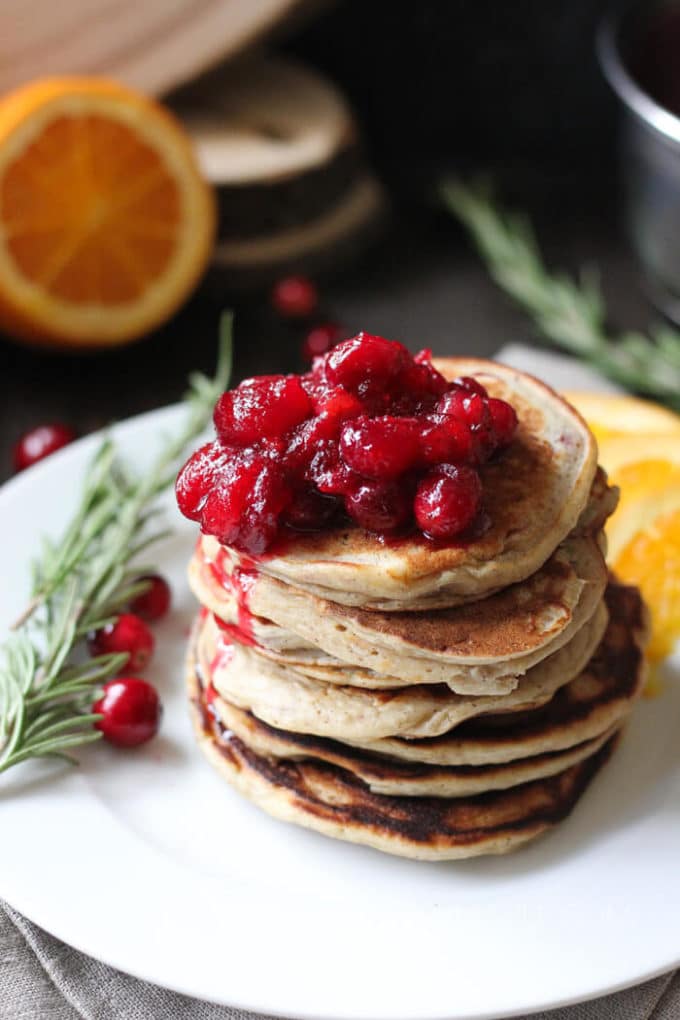 Ricotta Orange Pancakes stacked on a plate topped with cranberry sauce. 