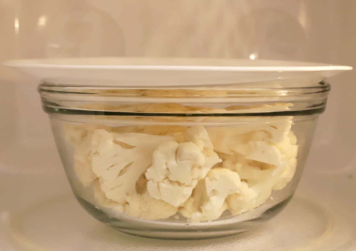 A bowl of cauliflower in a microwave.