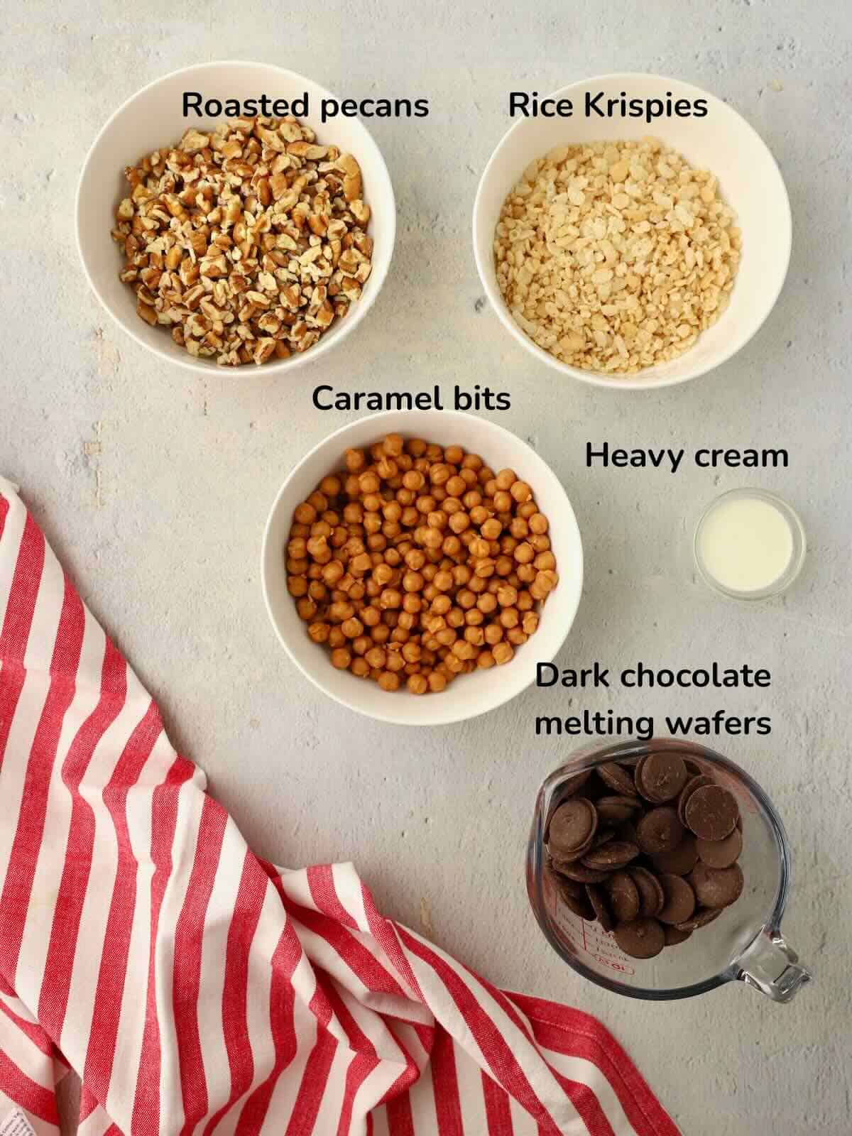 Ingredients for Dark Chocolate Billionaires include, caramel bits, chopped pecans, heavy cream, Rick Krispies, and dark Chocolate melting wafers. 