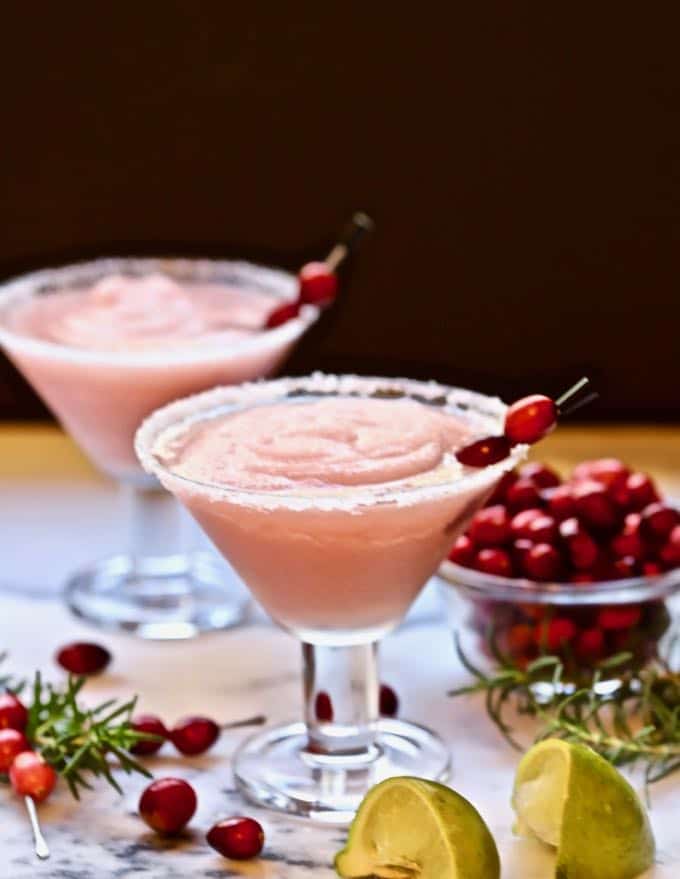 Two margarita glasses full of frozen cranberry margaritas.