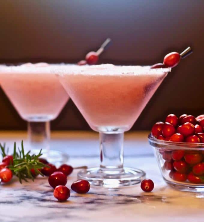 Two cranberry margaritas garnished with fresh cranberries. 