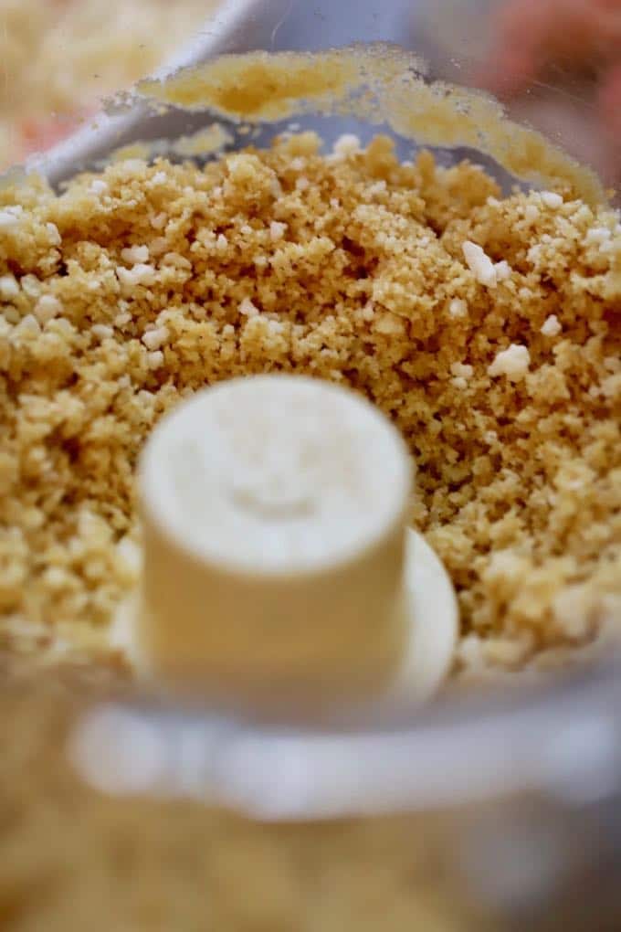 Ritz cracker crumbs in the bowl of a food processor.