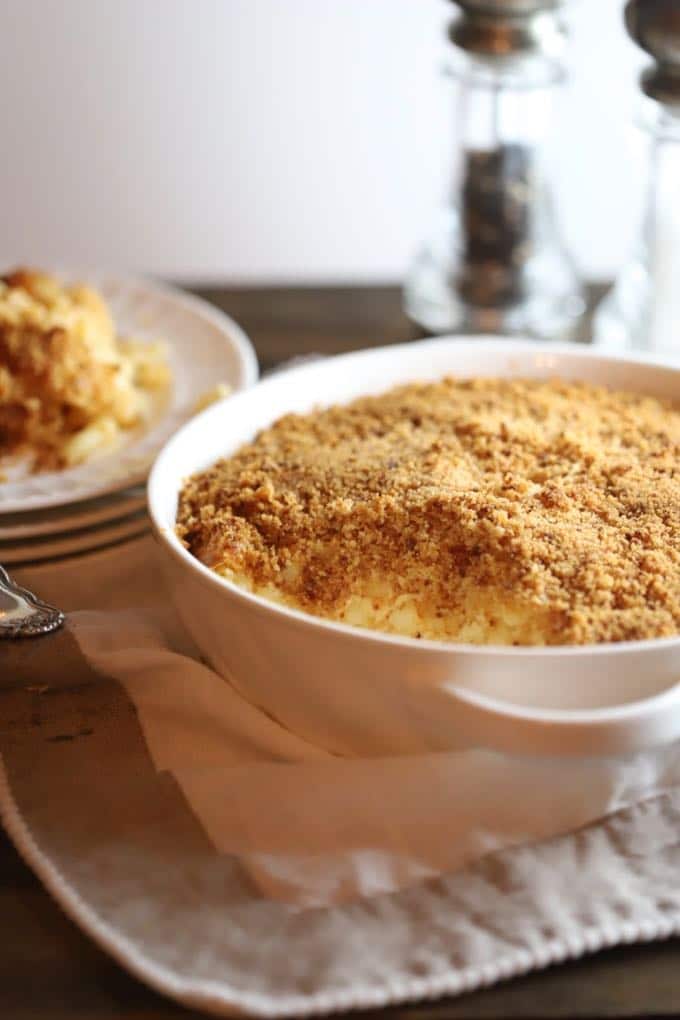 A white round casserole dish full of mac and cheese and topped with a crispy Ritz cracker crust.