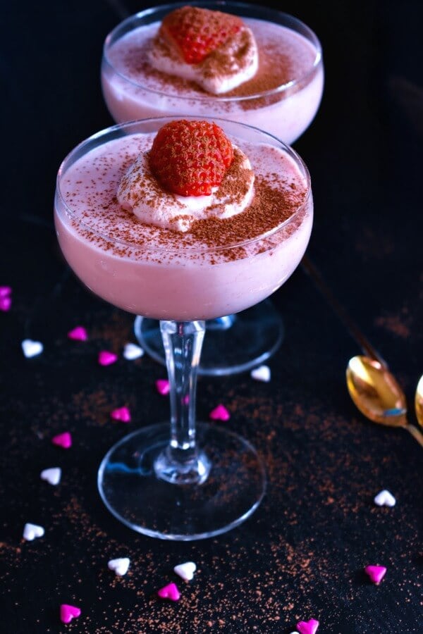 Strawberry Mousse in champagne glasses topped with a strawberry. 