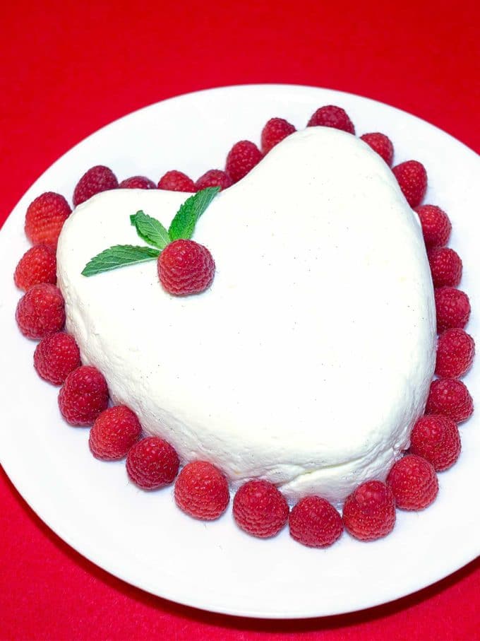 Coeur A La Creme Valentine's Day Dessert in the shape of a heart garnished with fresh raspberries.