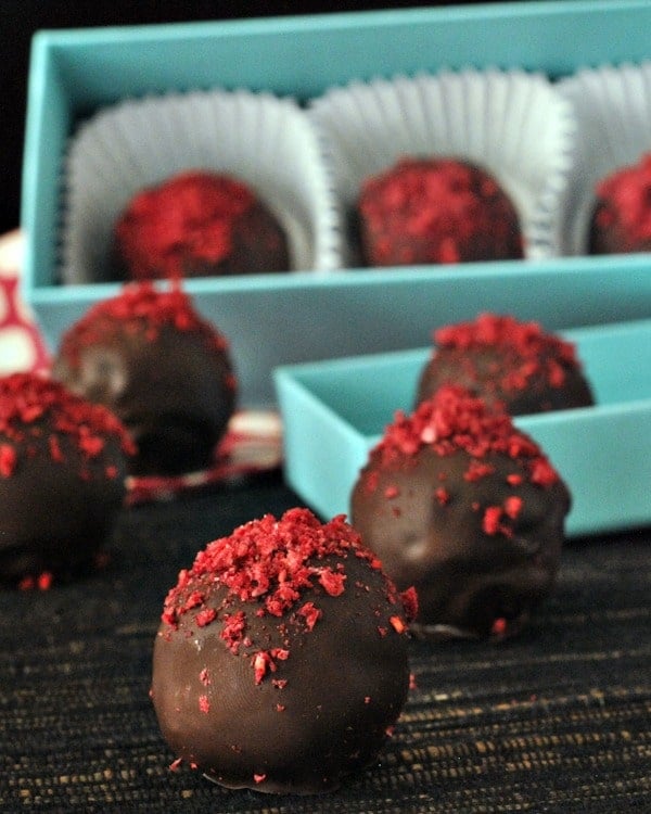 Raspberry Dusted Chocolate Fudge Brownie Truffles in a blue box with paper candy holders. 