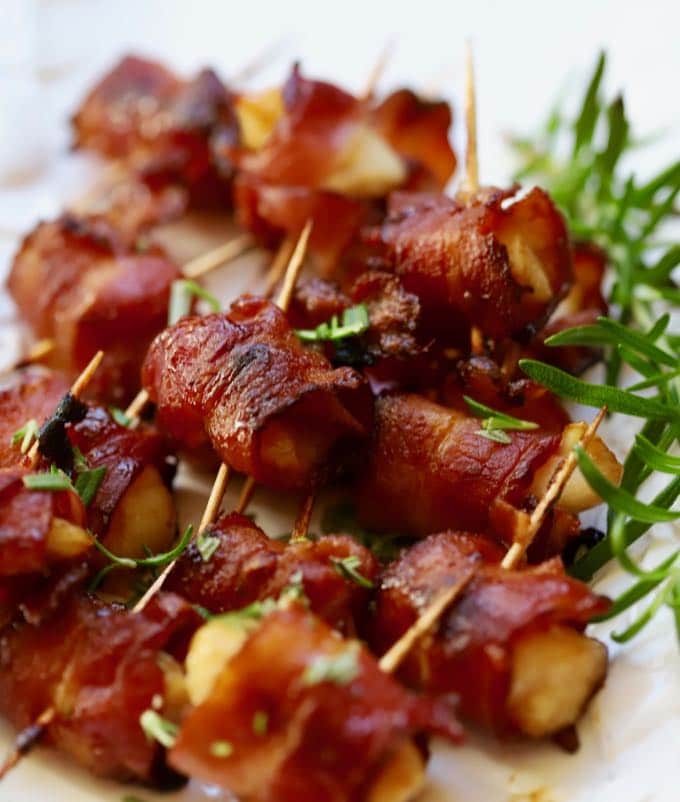 Baked Easy Marinated Bacon Wrapped Scallops served on a plate and garnished with fresh rosemary.