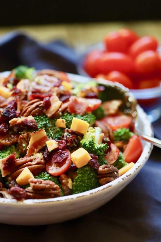 Close-up photo of Easy Southern Broccoli Salad topped with pecans, bacon and cheddar cheese with spoon ready to eat