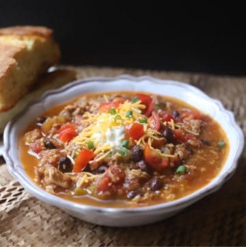 Hearty Chicken Chili Verde in a white bowl ready to serve with a side of cornbread