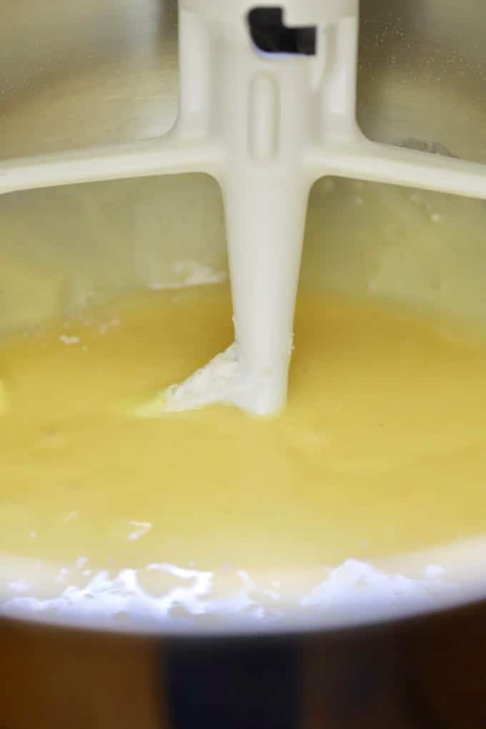 Mixing cake batter in a metal bowl with an electric mixer. 