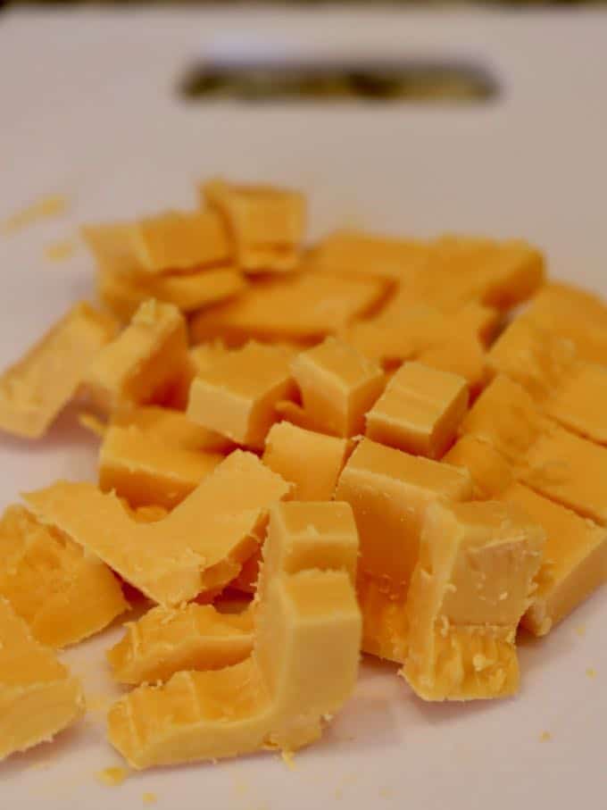 Chunks of cheddar cheese on a cutting board. 