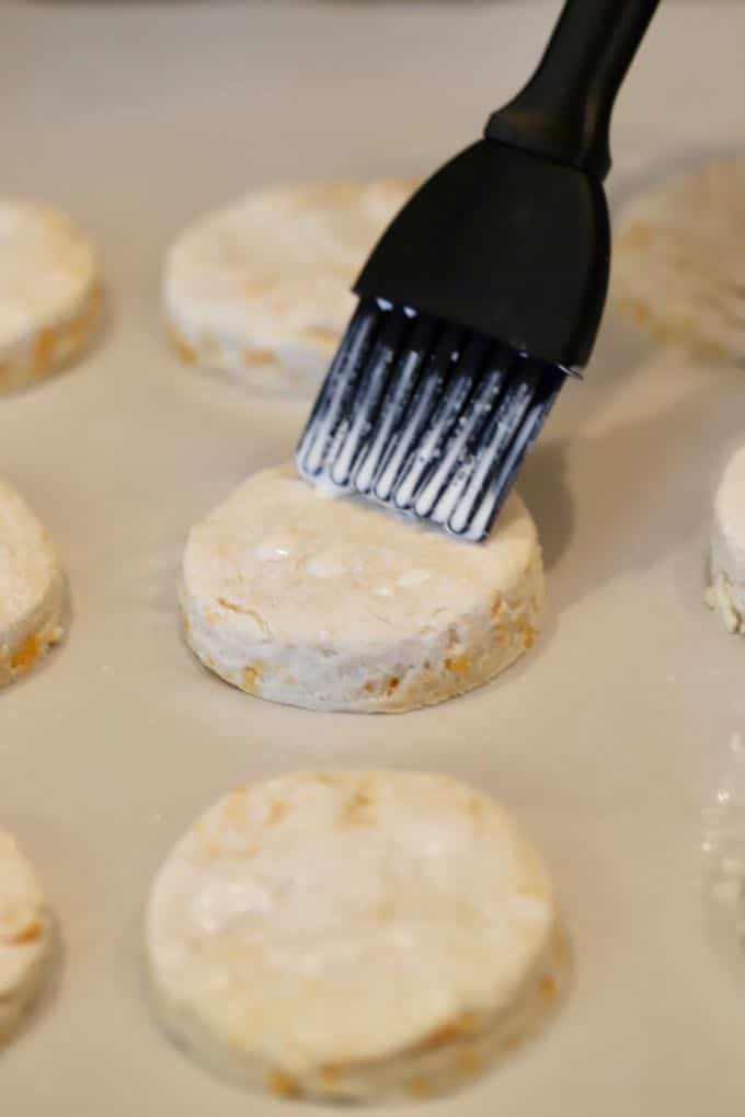 Brushing cream on raw biscuit dough to help them brown. 