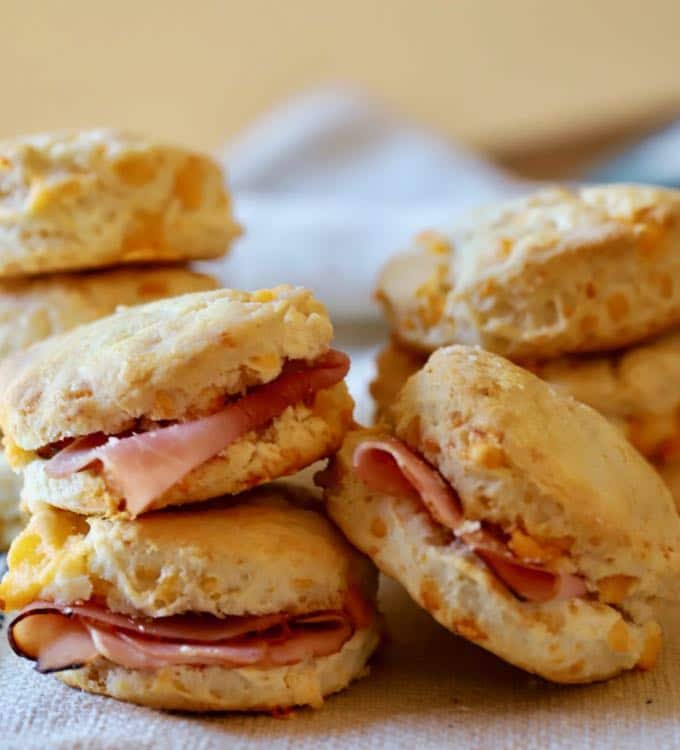 Several cheddar biscuits with a slice of ham in the middle.