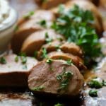 Pork Tenderloin with Mustard Sauce garnished with parsley and sitting on a baking sheet