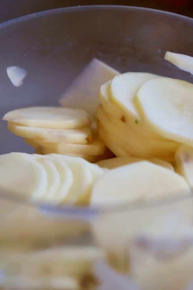 Sliced Potatoes in a food processor for Southern Cheesy Scalloped Potatoes