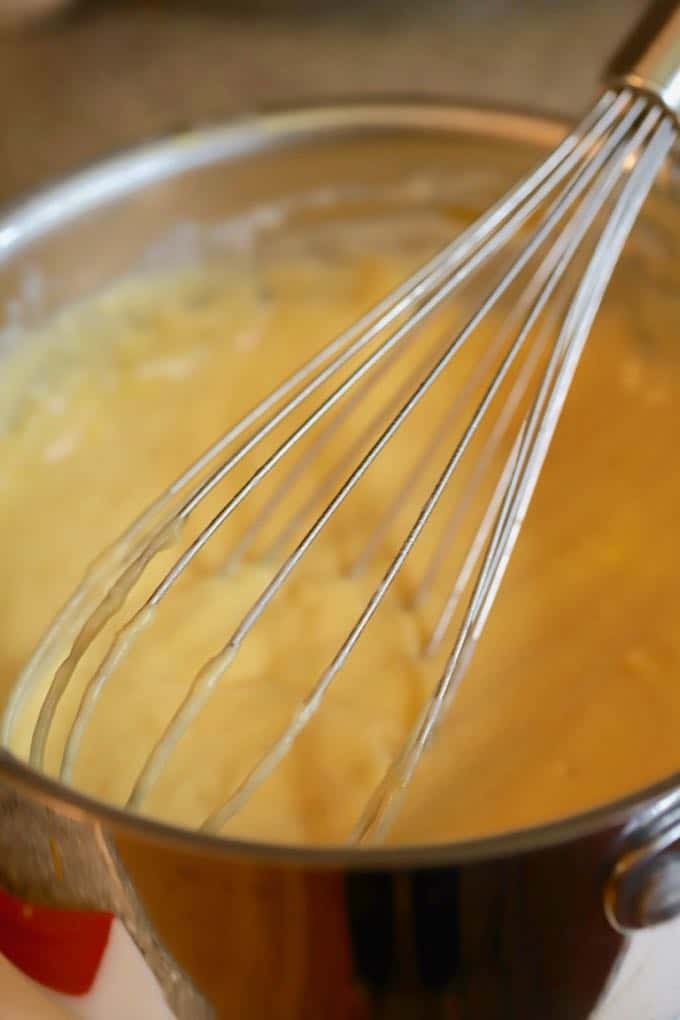 Melting cheese in the sauce for Southern Cheesy Scalloped Potatoes