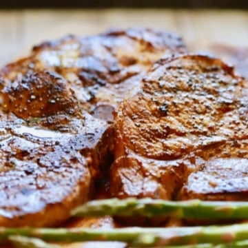 Easy Grilled Pork Chops and Marinade with pork chops right off of the grill on a wooden cutting board resting