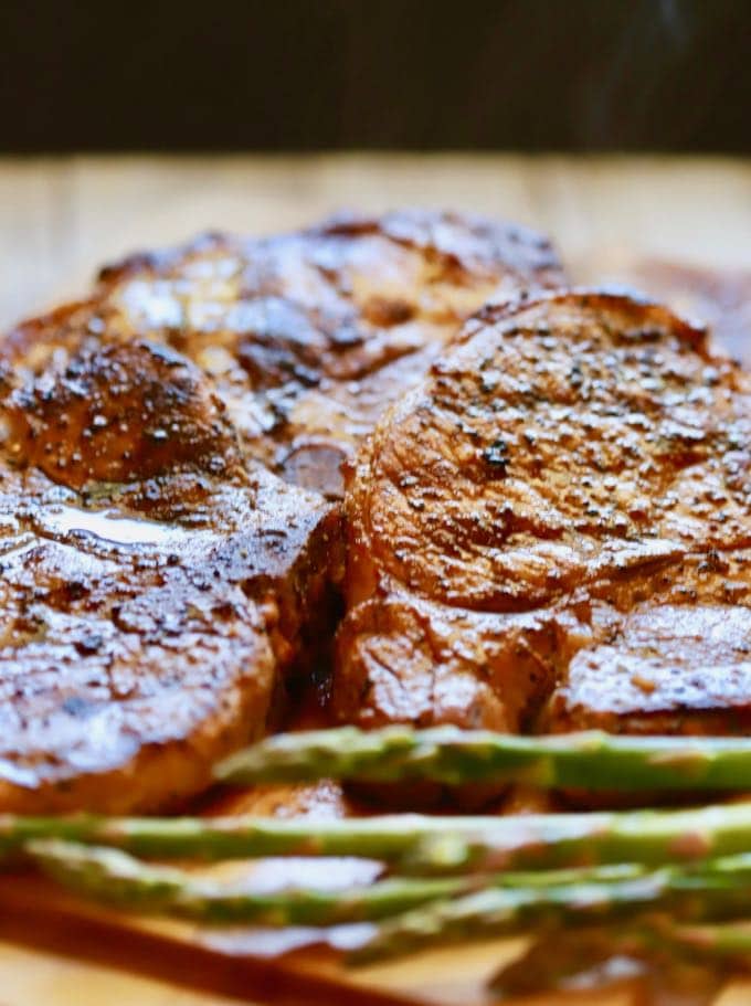 Easy Grilled Pork Chops and Marinade with pork chops right off of the grill on a wooden cutting board resting