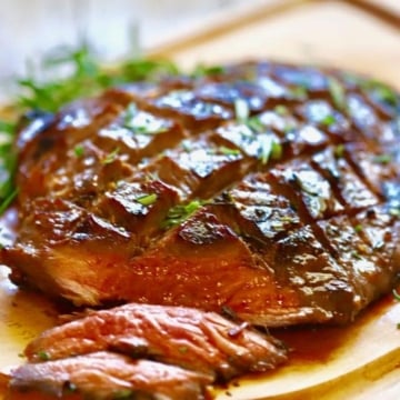 Ultimate Grilled Flank Steak on a cutting board with a few slices cut