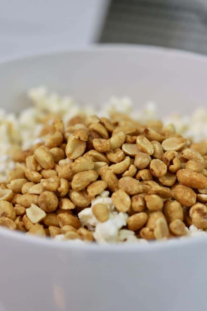 A bowl of popcorn topped with peanuts for Caramel Corn with Dark Chocolate Drizzle