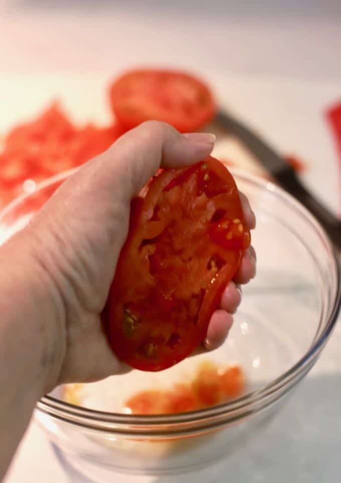 Seeding a tomato by hand, by squeezing out the seeds.