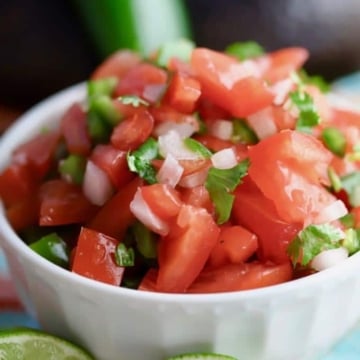 Easy homemade Pico de Gallo in a white bowl with cut limes in front