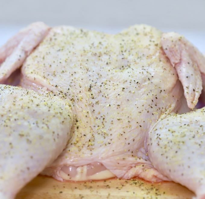 Kosher salt and lemon pepper seasoning on a whole raw chicken.