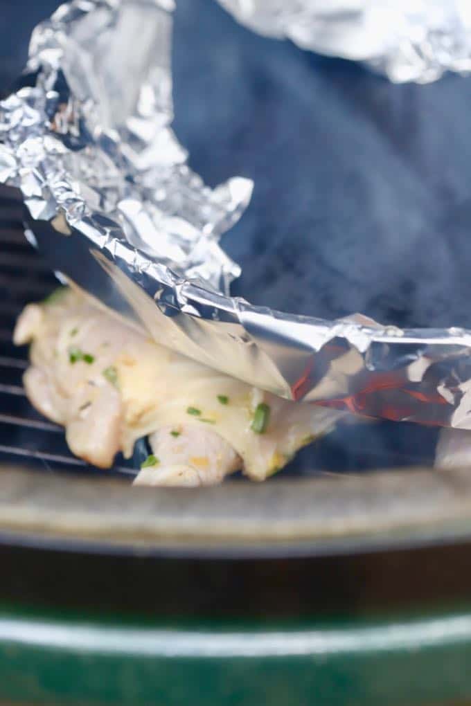 Weighing a butterflied chicken down with a cast iron pan on a grill.