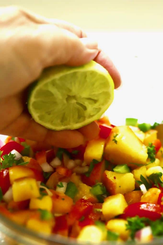 Squeezing lime juice over Easy Southern Fresh Peach Salsa