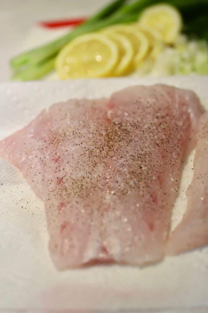 A piece of grouper seasoned with salt and pepper for Pan Fried Fish with Blistered Tomatoes