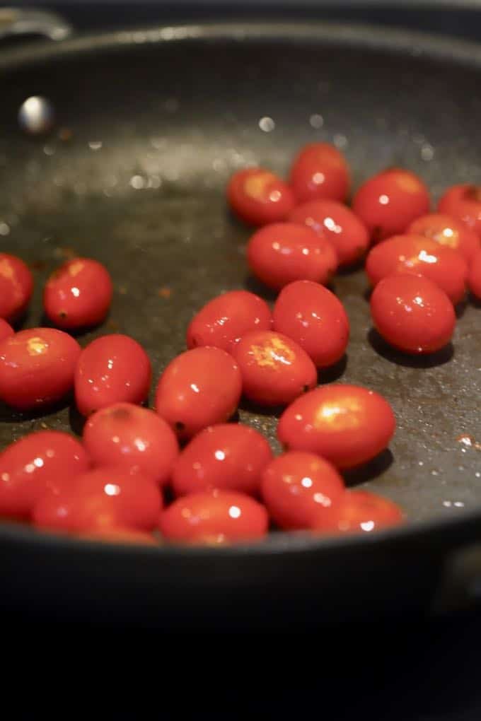 Cooking cherry tomatoes in a skillet for Pan Fried Fish with Blistered Tomatoes