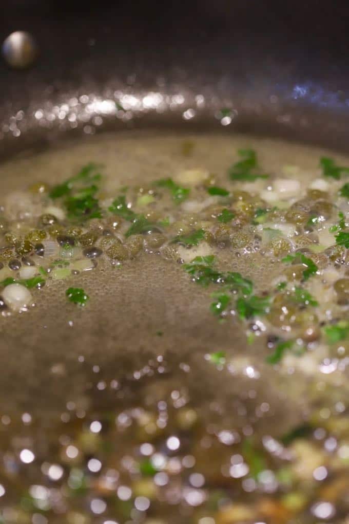 Lemon, butter and parsley in a skillet for Pan Fried Fish with Blistered Tomatoes