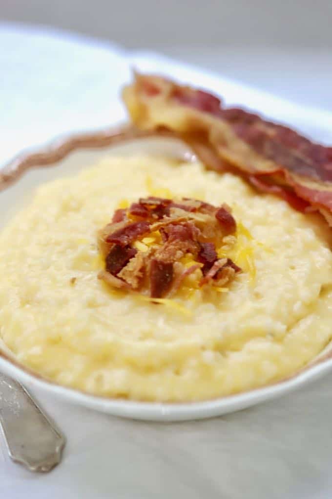 Southern Crockpot Easy Cheesy Grits topped with bacon in a bowl