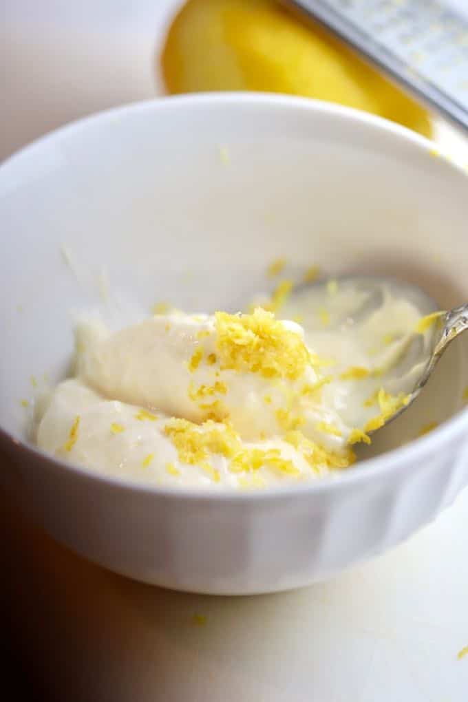 A small white bowl with mayonnaise and lemon zest. 