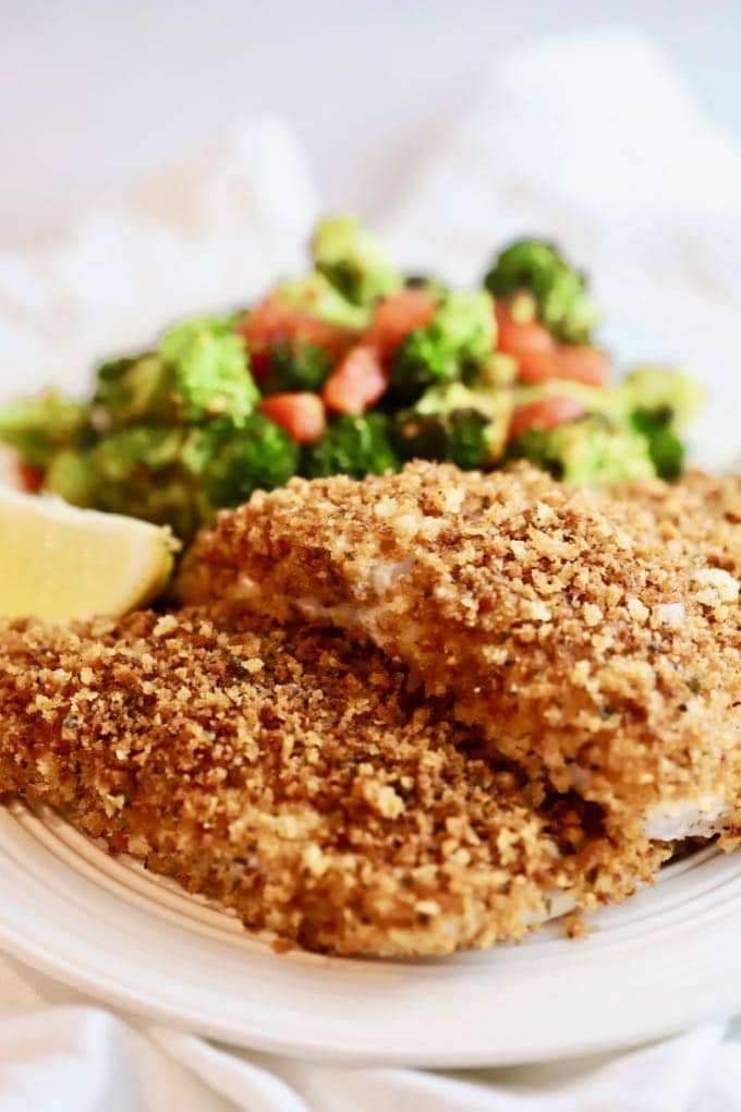 Easy Crispy Oven Baked Grouper fillets with lemon and broccoli and tomatoes on a plate