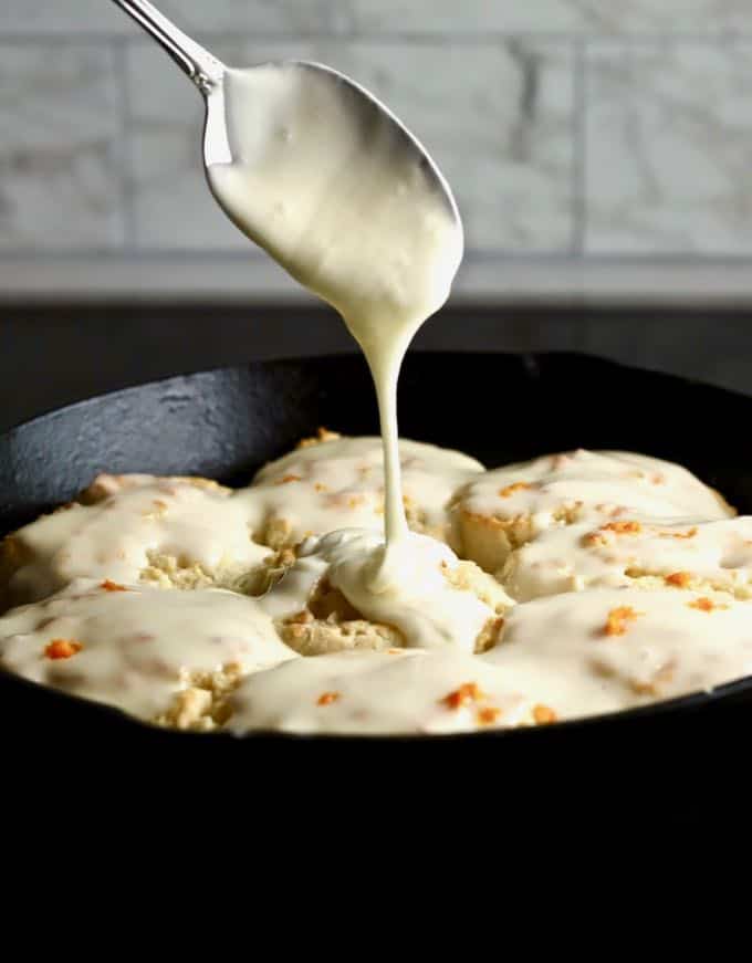 Easy Orange Cinnamon Rolls in a cast iron pan with orange cream cheese glaze being spooned on