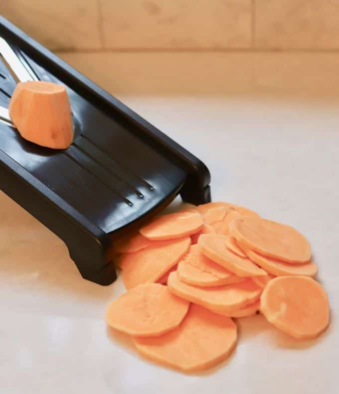 Cutting sweet potatoes with a mandolin for Baked Southern Candied Sweet Potatoes 