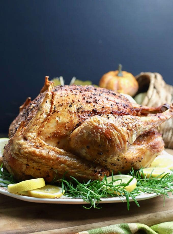 Dry Brined Fried Turkey without Oil garnished with lemon slices and rosemary