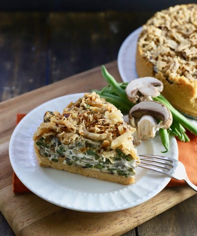 A slice of Green Bean Pie with Ritz Cracker Crust garnished with fresh mushrooms and green beans