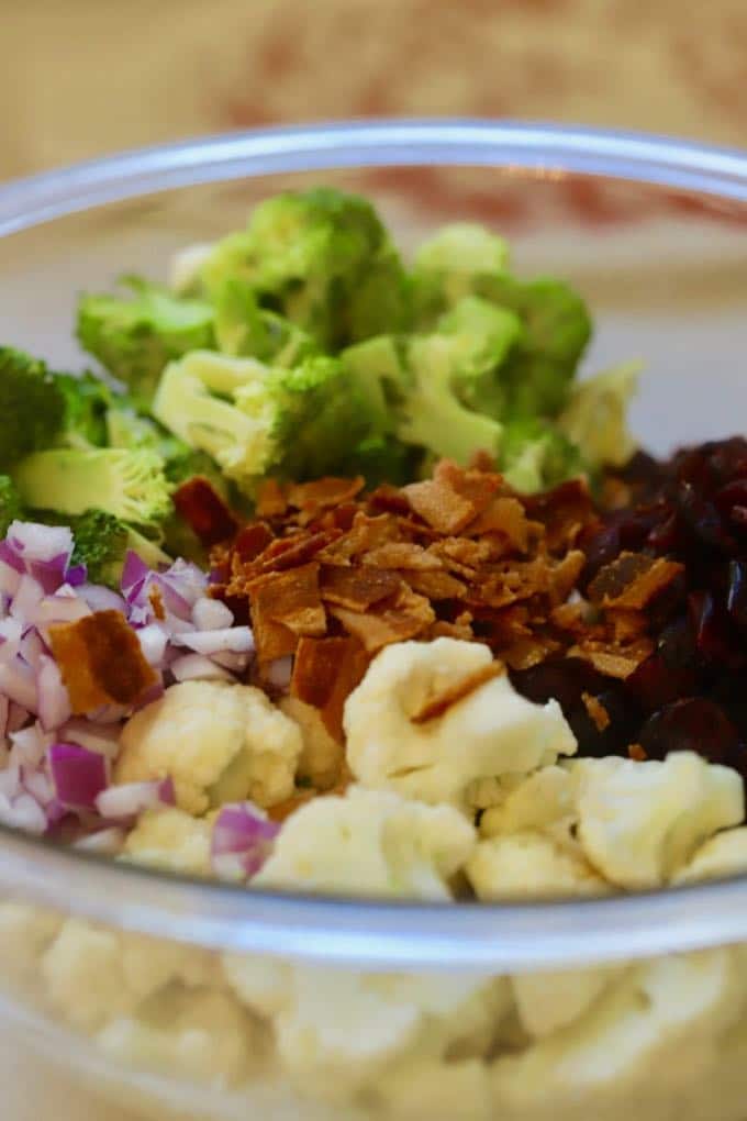 Broccoli Cauliflower Salad with Cranberries ingredients in a large clear bowl.