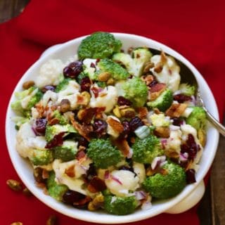 Broccoli Cauliflower Salad with Cranberries in a white serving dish on a red napkin