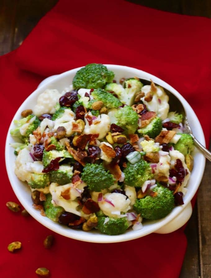 Broccoli Cauliflower Salad with Cranberries in a white serving dish on a red napkin