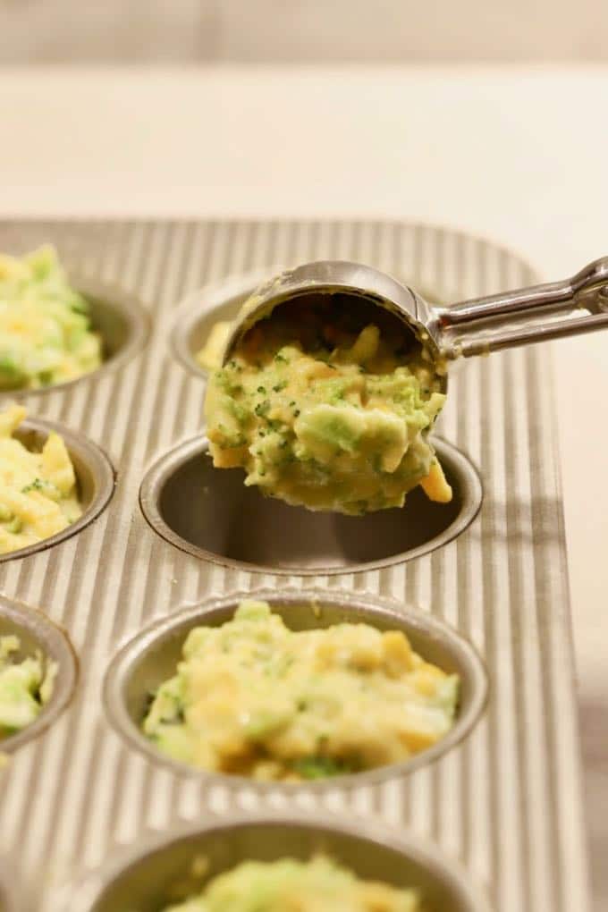 Using an ice cream scoop to add batter to muffin cups for Broccoli Cheddar Cornbread Muffins.