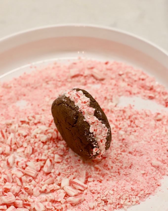 Rolling whoopie pies in crushed candy canes to make Easy Chocolate Peppermint Whoopie Pies.
