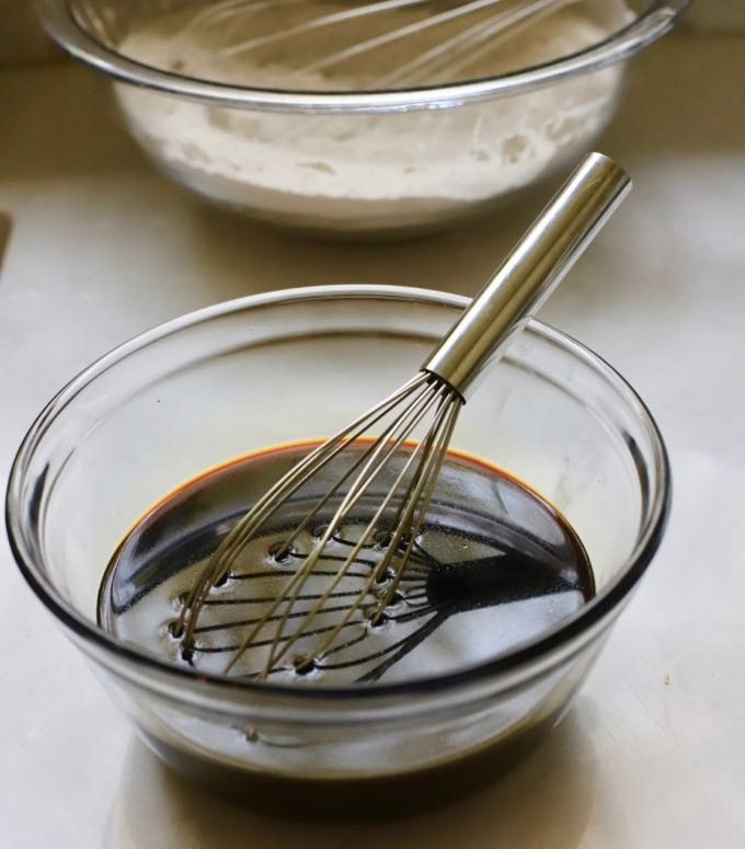 Mixing molasses and water in a clear glass bowl. 