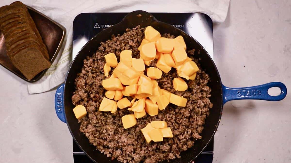 Cubes of processed cheese added to ground beef. 