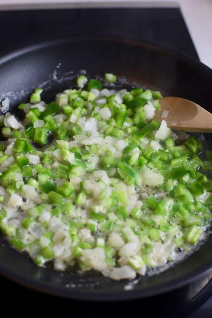 Cooking celery, bell pepper, and onion in a skillet to make shrimp creole.