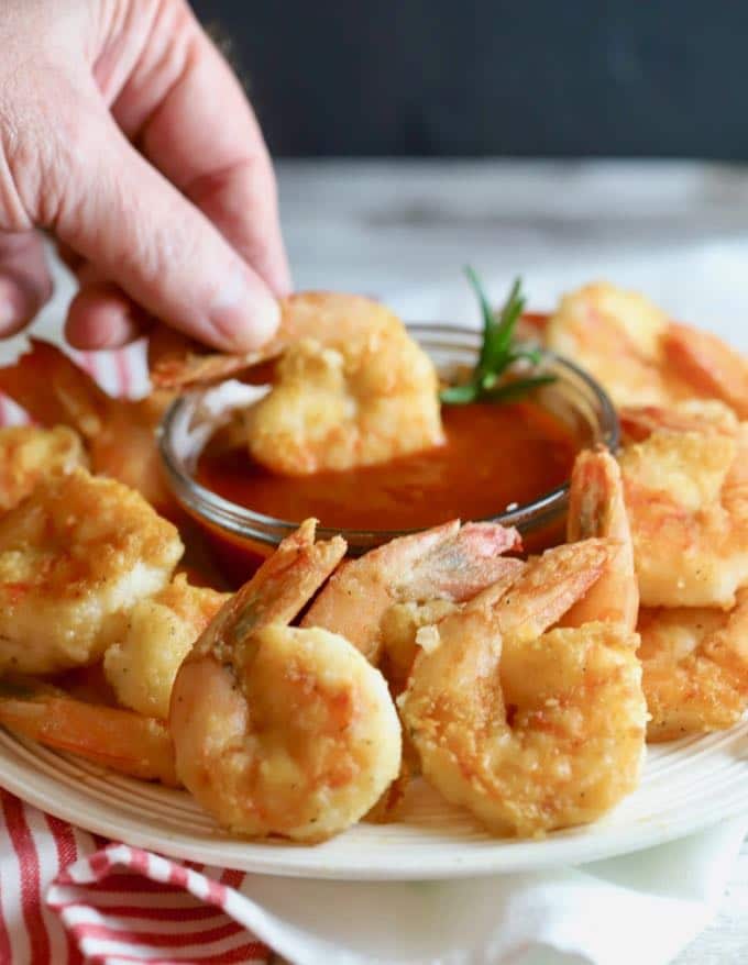 Dipping Easy Crispy Pan-Fried Shrimp in cocktail sauce. 