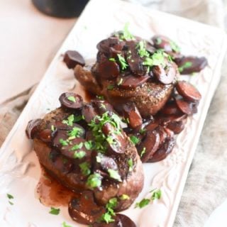 Two filet mignons with Mushroom Red Wine Sauce on a serving plate.