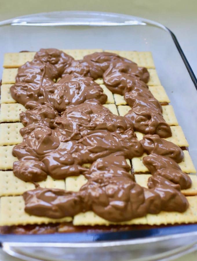 Melted chocolate topping is spread over crackers to make homemade copycat kit kat bars.